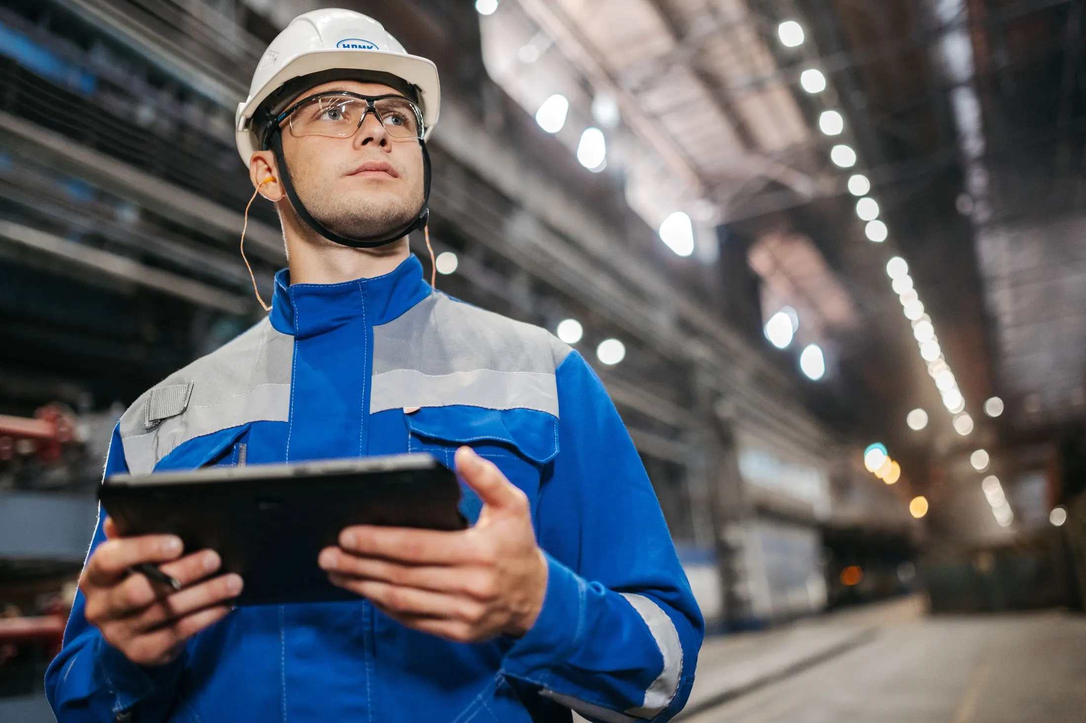 Ingeniero con casco consultando una tableta en una nave industrial